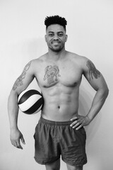 Fototapeta premium Black and white portrat of a man against white wall background with ball