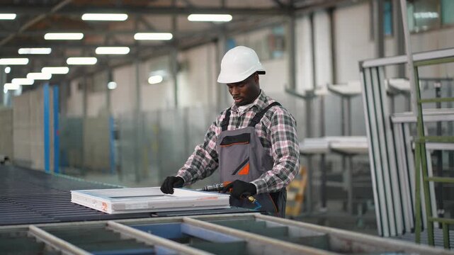 African american factory worker assembling pvc window frames