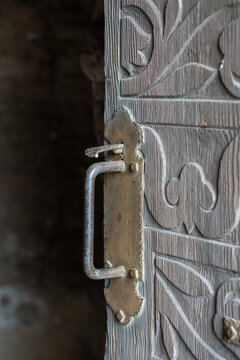 Detail of metal door handle on a hand-carved old wooden door