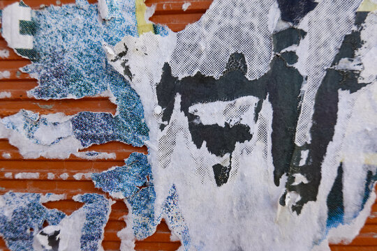 Close-up of weathered wall with peeling old advertising posters in shades of blue and white. Abstract urban background