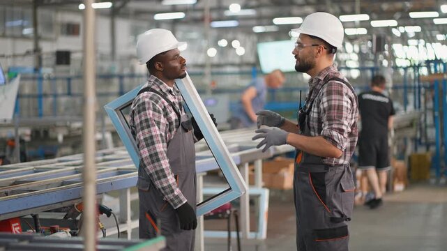 Factory workers shaking hands and discussing window frame production