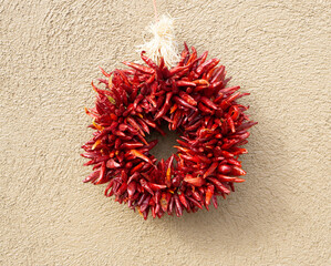 Festive red hatch chili pepper wreath on beige stucco wall © A. Brownfield Brown