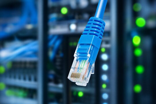 Blue RJ45 Ethernet Cable Hanging Down in Front of Dark Server Rack with Glowing LED Indicator Lights, Symbolizing Data Center Networking and Connectivity