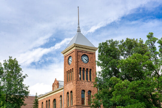 Clock tower on a red  brick building set against a bright blue sky