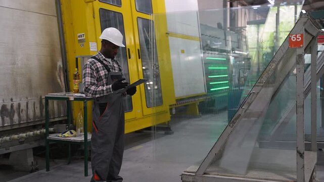 Factory worker inspecting glass sheet manufacturing process