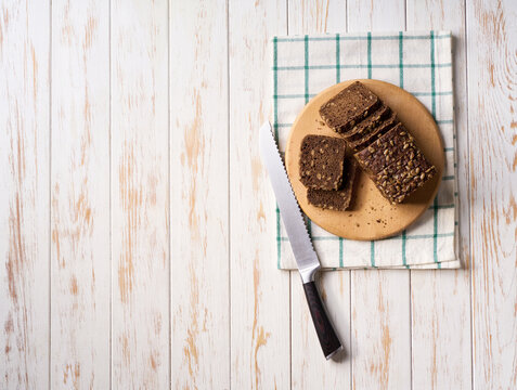 freshly baked wholemeal rye bread with sunflower seeds on white kitchen table, copy space for text. Top view.