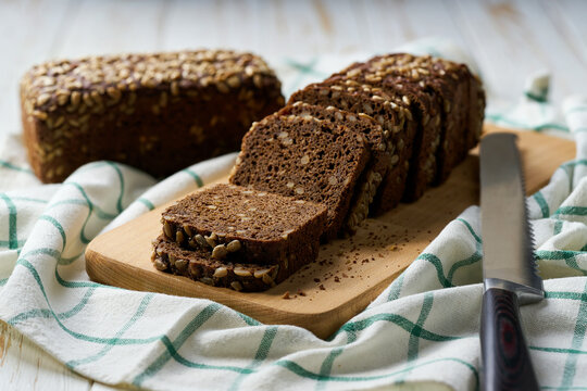 wholemeal rye bread with sunflower seeds on white kitchen table, selective focus.