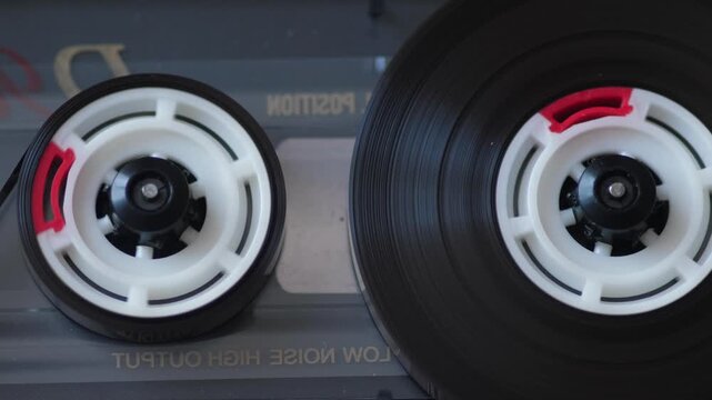 Close up of spinning reels of an analog audio cassette tape playing music. Vintage cassette deck player creating a nostalgic and retro mood