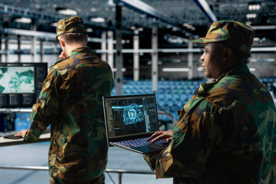 Soldier monitoring AI assisted defense systems in military data command center; Army expert overseeing real time analytics powered by artificial intelligence in army operations hub.