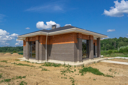 Newly constructed brick house on a clear sunny day surrounded by nature in a rural setting