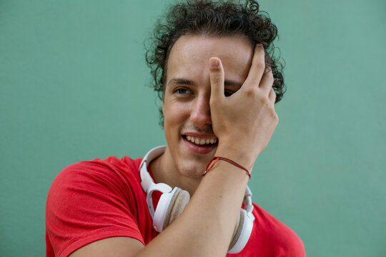 Playful young man covering one eye with hand and smiling