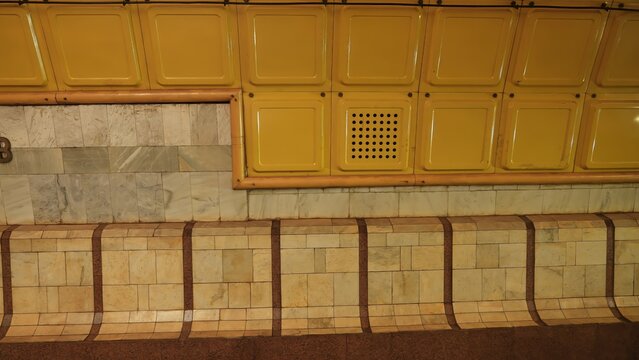 Close up of a subway station tiled wall showcasing classic yellow and marble textures. Concept: urban design, architectural detail, transportation infrastructure, vintage style.