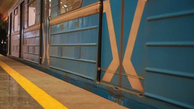 Close up of blue subway train at a platform with yellow safety line. Concept of urban transportation, travel, public transit, safety, and commuting.