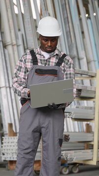 Factory worker using laptop for inventory control in warehouse