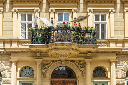 Flower-filled balcony with a wrought iron railing on a historic apartment facade on Sz&eacute;chenyi utca in Budapest, Hungary