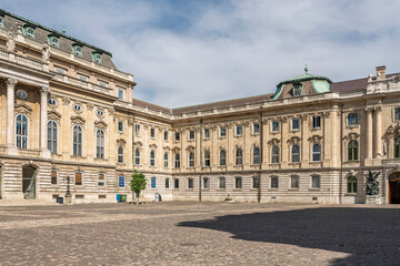 Obraz premium Wide cobblestone courtyard view of a long baroque wing of Buda Castle with rows of arched windows in Budapest, Hungary