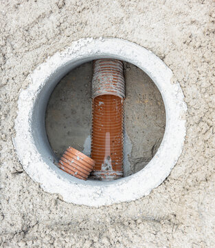 High angle view of orange plastic drainage pipes in a concrete inspection manhole shaft