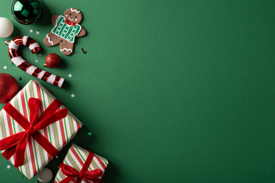 Christmas presents with red ribbons, gingerbread cookie and ornaments on green background for holiday greeting