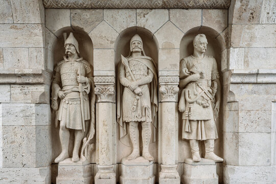 Three carved stone Hungarian warrior statues standing in arched wall niches at Fisherman's Bastion, Budapest