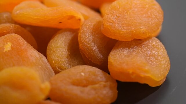 Apricot dried fruits on dark grey background. Ripe Organic Apricots fruit rotating. Dried apricots close-up. Close up. Heap of dried apricot. Vegan food, fiber. Border design