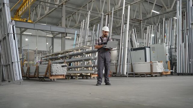 Engineer with laptop supervising a factory warehouse