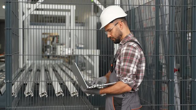 Industrial engineer programming automated machinery with laptop