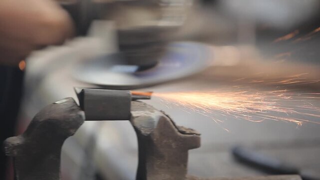 Close-up of a worker using an angle grinder on a piece of metal clamped in a vise, sending bright sparks flying. Industrial metalworking and workshop concept.
