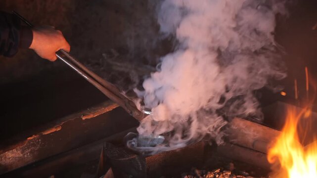 Close-up of a blacksmith quenching a hot axe head in liquid, creating a thick cloud of white smoke. Traditional metal forging, tool making, and artisan craftsmanship concept.
