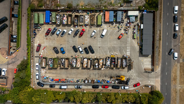 Aerial view of Stevenage Recycling Centre with rows of waste containers and parked cars on an asphalt surface in Stevenage, England, United Kingdom.