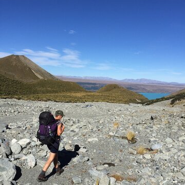 A female hiker and rock climber walks out of a remote alpine valley in Mt Cook National Park, New Zealand