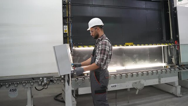 Factory worker operating automated glass cutting machine