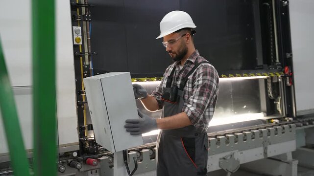 Industrial male worker operating a metal bending machine in a factory