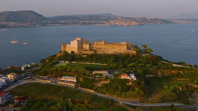 Panoramica aerea in movimento della fortezza aragonese di Baia, scogliera e bellezze paesaggistiche campane.