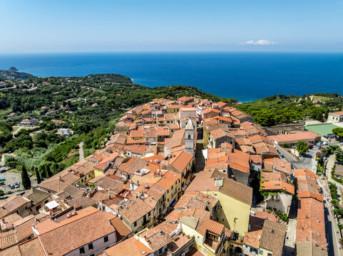 Aerial view of the historic town of Capoliveri featuring terracotta rooftops, narrow streets, and a church tower overlooking the Mediterranean Sea in Capoliveri, Tuscany, Italy.