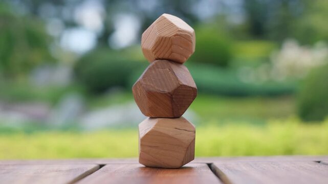Hand stacking faceted wooden stones playing Tumi Ishi game of balance and mindfulness