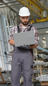 Industrial engineer using a laptop in a factory warehouse