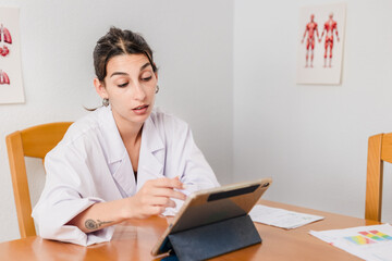 Fototapeta premium Female doctor online consulting patient using tablet