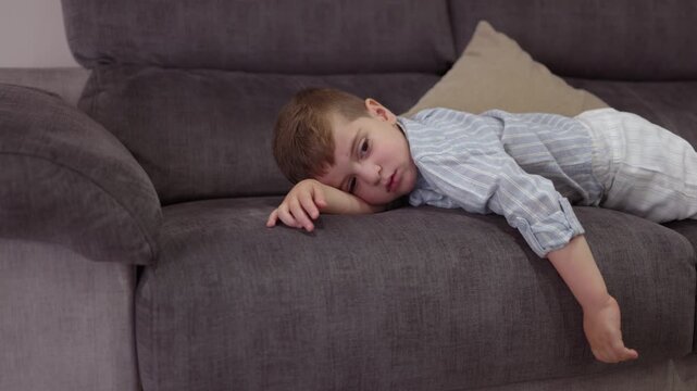 Tired little boy waking up on the sofa