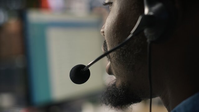 Close-up of a call center agent speaking through an audio headset while handling complaints and supporting dissatisfied clients with customer service issues in an office workplace.