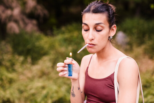 Young woman lighting a marijuana joint relaxing outdoors
