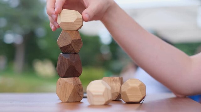 Man placing a wooden Tumi Ishi balancing block on a tower in a Japanese garden, close up