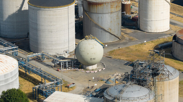 Aerial view of Tanklager featuring large industrial storage tanks and a spherical pressure vessel connected by a network of pipes in Gelsenkirchen, North Rhine-Westphalia, Germany.