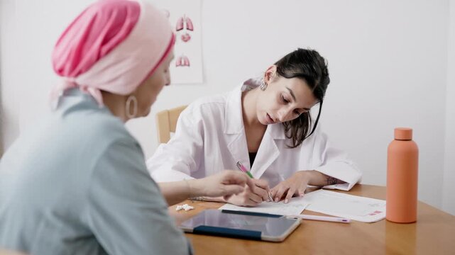 Young female doctor prescribing medication to cancer patient