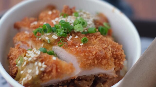 Delicious deep-fried chicken with savory sauce on rice bowl