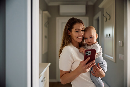 Happy mother taking selfie with her baby boy at home.