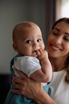 Cute baby boy enjoying in mother's arms at home.