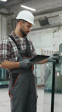 Factory worker checking glass panels inventory