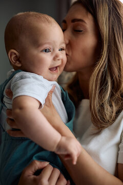 Baby boy being kissed by his mother at home.