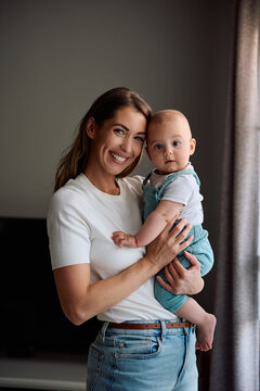 Portrait of happy mother and her baby boy at home looking at camera.
