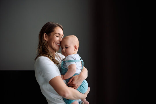 Affectionate mother holding her baby boy at home.